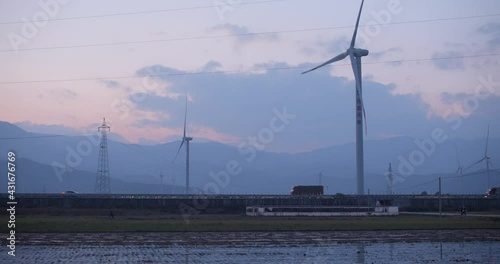 A large Chinese windfarm located in the valley of Sichuan located in between traditional chinese farms during sunset photo