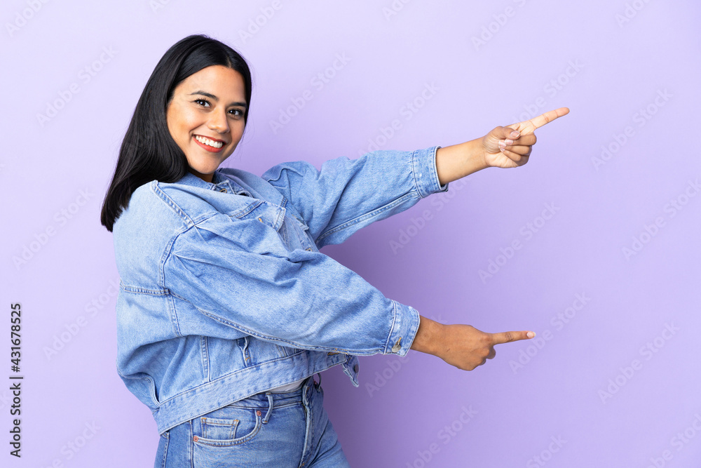 Young latin woman woman over isolated background pointing finger to the side and presenting a product Young latin woman woman over isolated background pointing finger to the side and presenting a product
