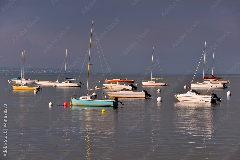 	Boats on the sea at the end of the day in a gray tone at Andernos-les-bains, ostreicole commune located on the northeast shore of Arcachon Bay, in France
