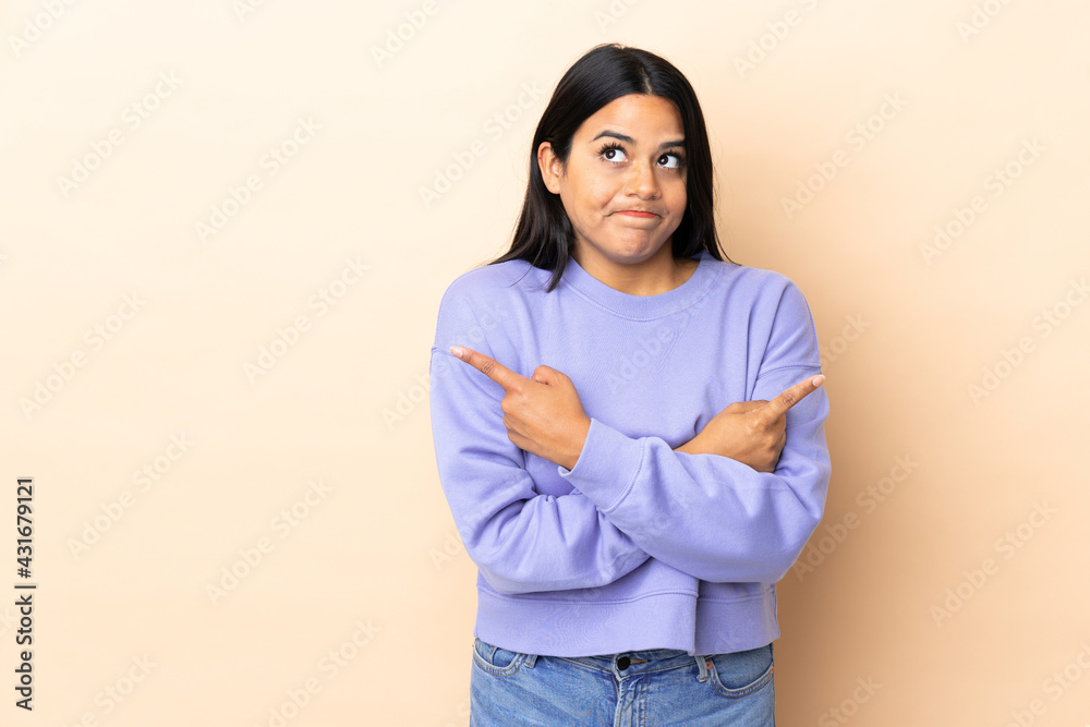 Young latin woman woman over isolated background pointing to the laterals having doubts Young latin woman woman over isolated background pointing to the laterals having doubts