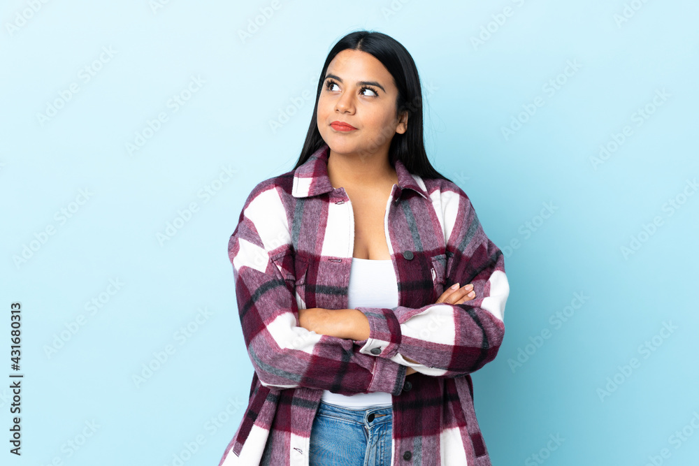 Young latin woman woman isolated on blue background looking to the side Young latin woman woman isolated on blue background looking to the side