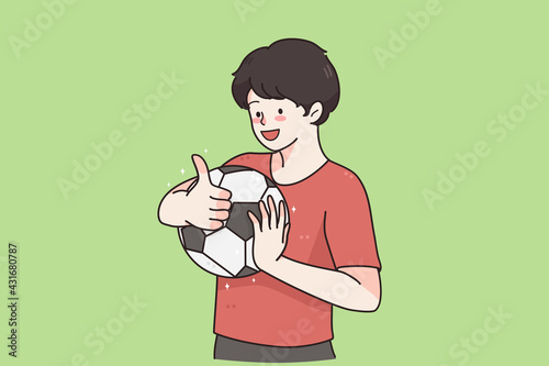 Boy football player concept. Young smiling child boy cartoon character standing holding soccer ball and showing thumbs up sign over green background vector illustration 