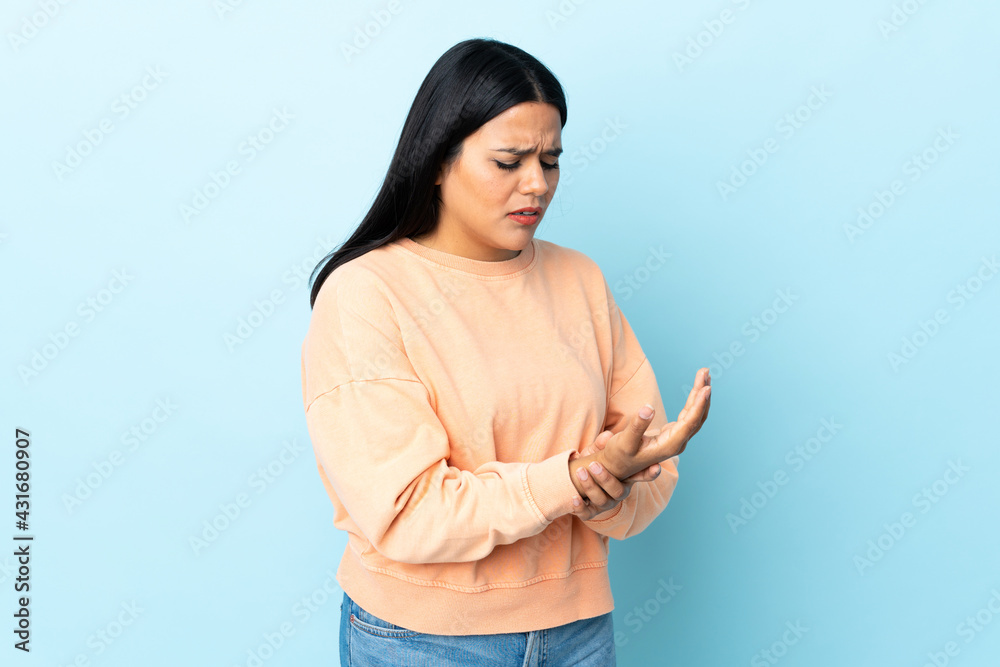Young latin woman woman isolated on blue background suffering from pain in hands Young latin woman woman isolated on blue background suffering from pain in hands