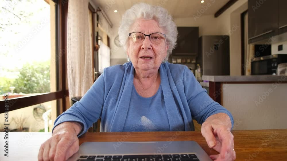 happy senior woman at home calling family with laptop computer and internet close up face camera view