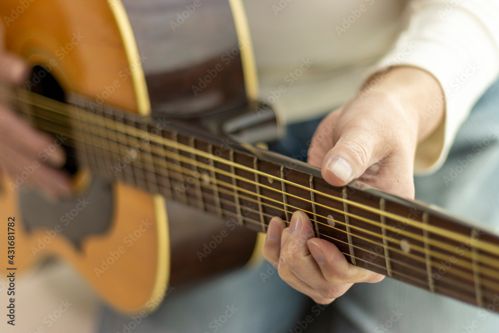 ギターの練習をするシニア女性のイメージ（60代、日本人）