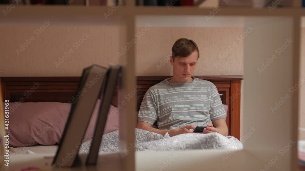 Serious man on social media with phone in bed