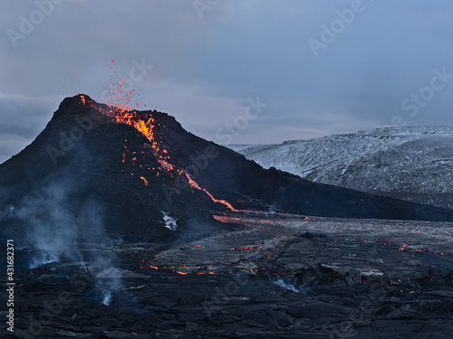 Stunning view of recently erupted volcano in Geldingadalir valley near Fagradalsfjall mountain, Grindavík, Reykjanes peninsula, southwest Iceland with hot lava flows and smoke in the evening. photo