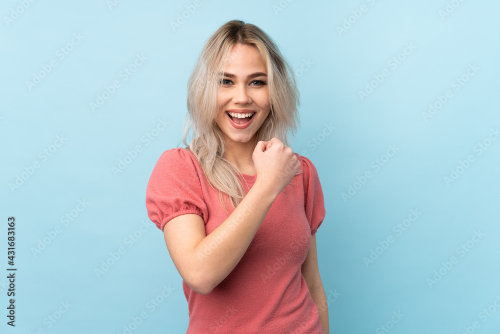 Teenager girl over isolated blue background celebrating a victory