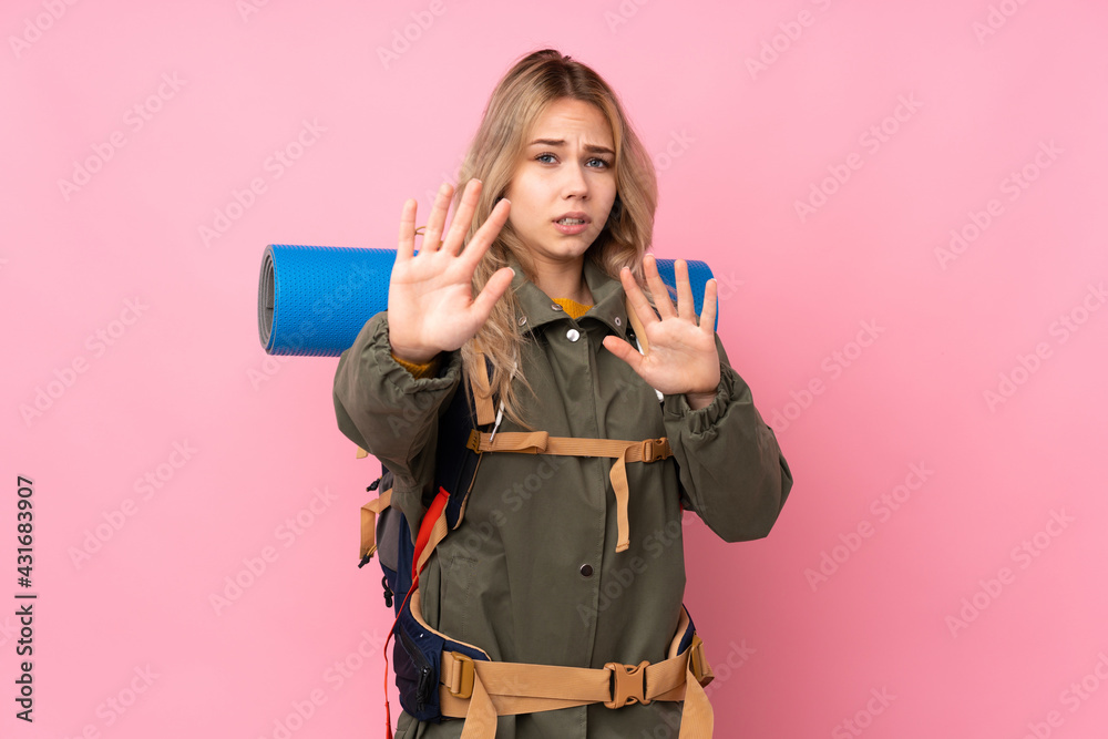 Teenager Russian mountaineer girl with a big backpack isolated on pink background nervous stretching hands to the front Teenager Russian mountaineer girl with a big backpack isolated on pink background nervous stretching hands to the front