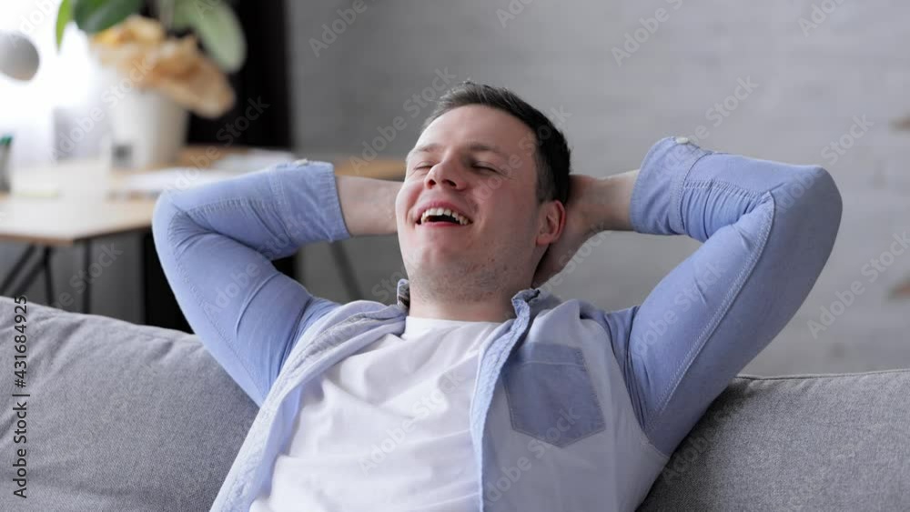 Lazy relaxed Caucasian young man resting on comfortable couch hold hands behind head eyes closed breath fresh air dream lounge on sofa at home enjoy stress free nap at home. Slow motion. Lazy relaxed Caucasian young man resting on comfortable couch hold hands behind head eyes closed breath fresh air dream lounge on sofa at home enjoy stress free nap at home. Slow motion.