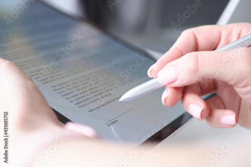 Woman hand holds stylus and puts an electronic signature in contract on tablet photo