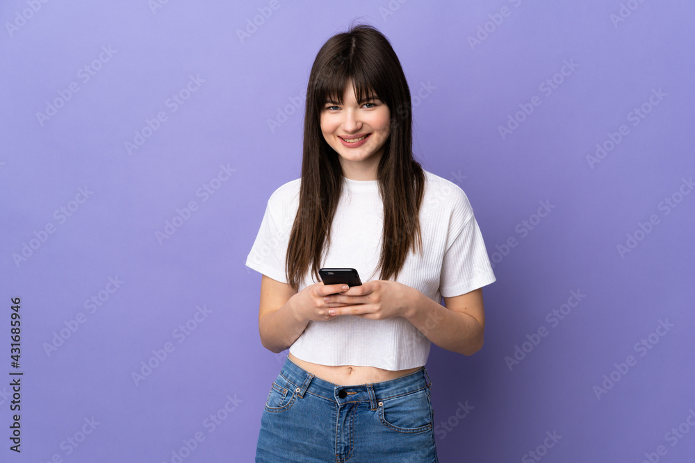 Young Ukrainian woman isolated on purple background sending a message with the mobile Young Ukrainian woman isolated on purple background sending a message with the mobile