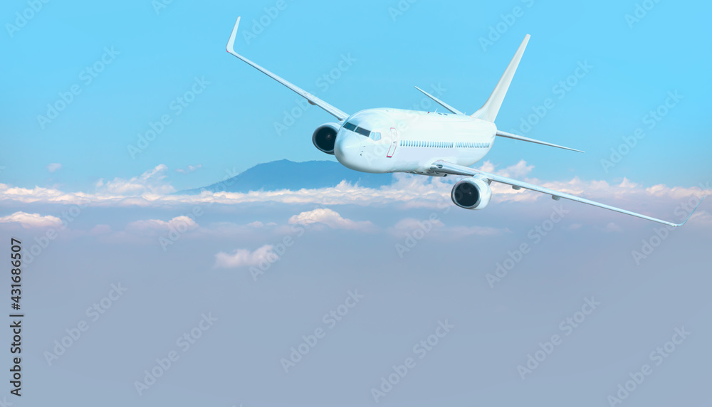 Fototapeta premium A passenger airplane flying over the clouds and a mountain peak in the background