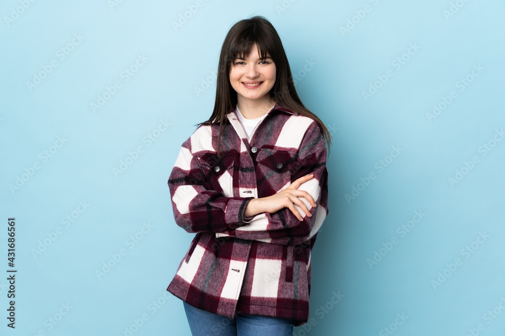 Teenager Ukrainian girl isolated on blue background keeping the arms crossed in frontal position