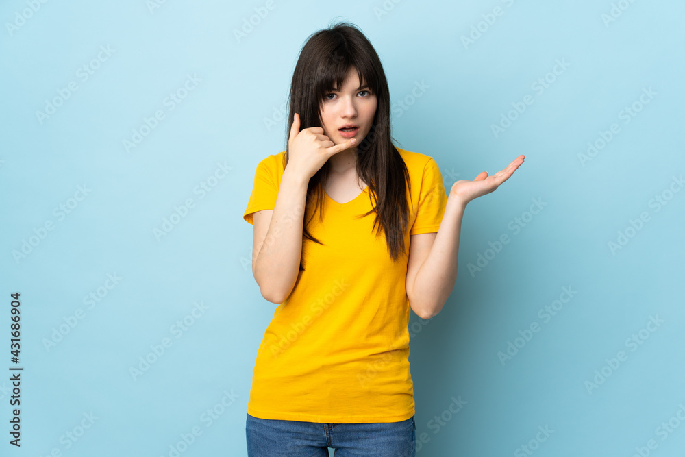 Teenager Ukrainian girl isolated on blue background making phone gesture and doubting Teenager Ukrainian girl isolated on blue background making phone gesture and doubting
