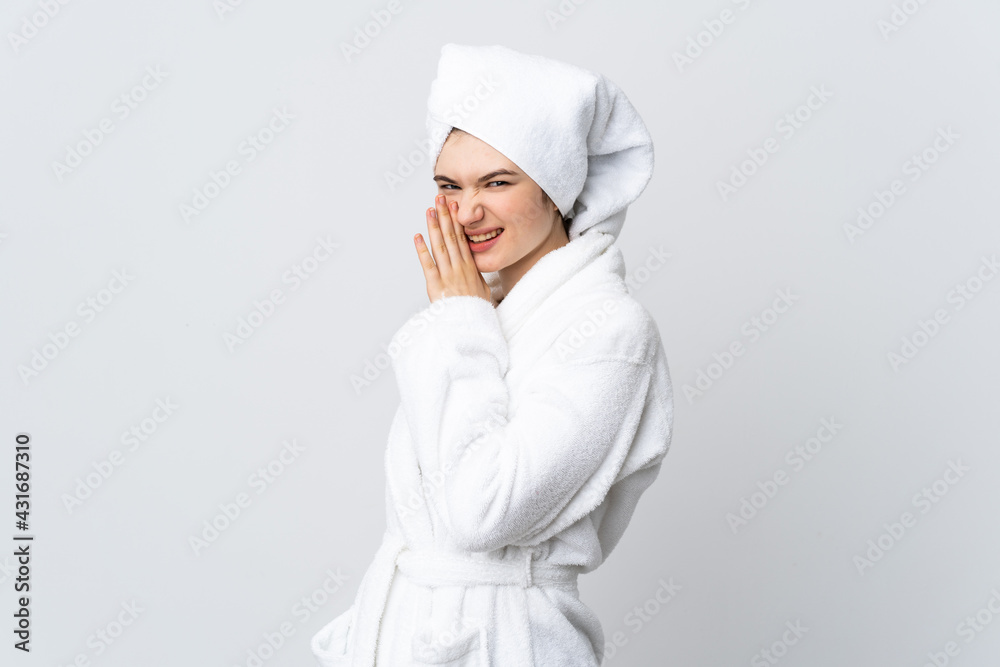 Teenager girl in a bathrobe isolated on white background whispering something