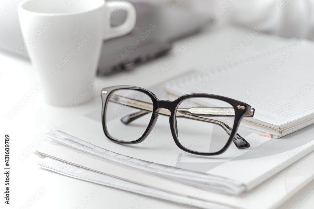 Closeup black eyeglasses on a folder with documents on desk. A female work on a background Closeup black eyeglasses on a folder with documents on desk. A female work on a background