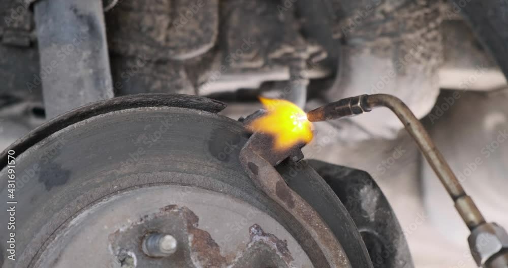 heating with a blowtorch of an old rusted bolt on the car's brake