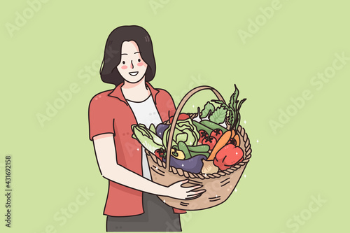 Healthy food and vegetarian diet concept. Young happy positive woman cartoon character standing and holding basket with fresh raw organic vegetables and fruits in hands vector illustration 