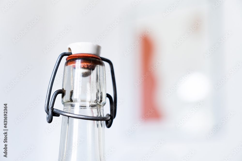Une bouteille en verre transparent avec un bouchon refermable en capsule de porcelaine - obrazy, fototapety, plakaty 