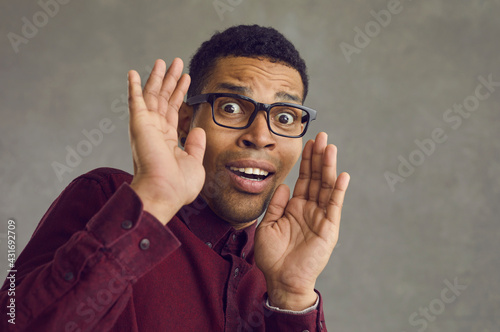 Fotografi Studio portrait of black man in glasses gasping and panicking scared by something terrible