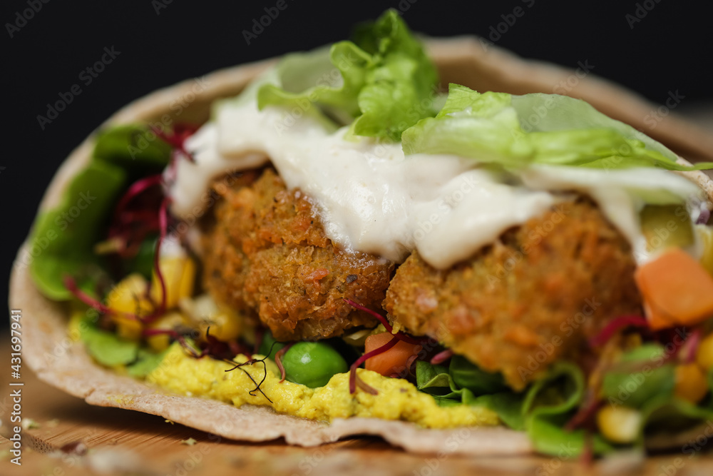 Close up of juicy healthy vegetarian tortilla on wooden plate