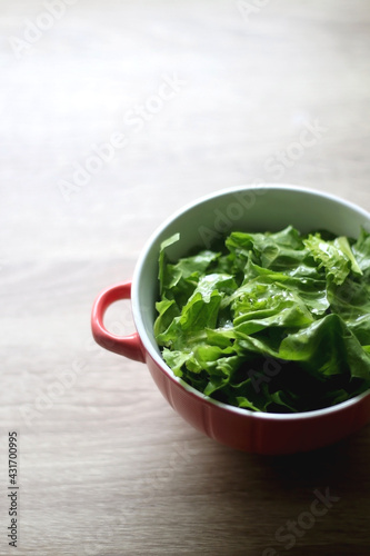 Bowl of lettuce on wooden table. Selective focus.