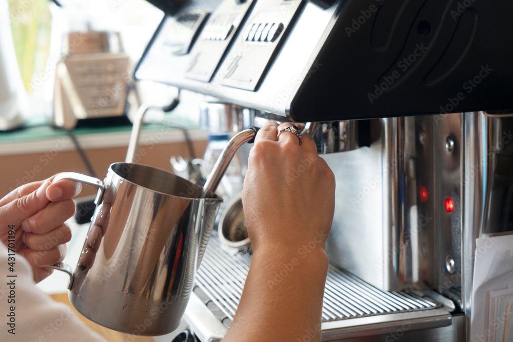 Barista whipping milk in metallic pitcher for cappuccino or latte - obrazy, fototapety, plakaty 