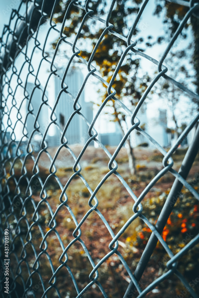 Downtown Los Angeles behind the mesh fence, focus on the fence