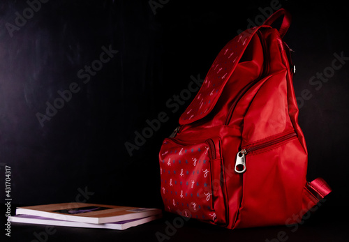 A school bag with books placed at one side, shot against blackboard in the background -Primary Education concept.