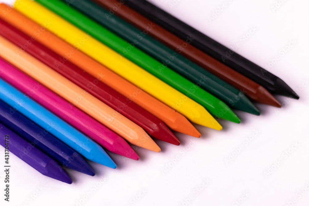Fototapeta premium High angle close up shot of crayon color sticks put on white background placed laterally adjacent to each other.