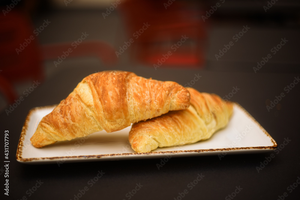 Two croissants on the table, breakfast outside in a restaurant. French building Two croissants on the table, breakfast outside in a restaurant. French building