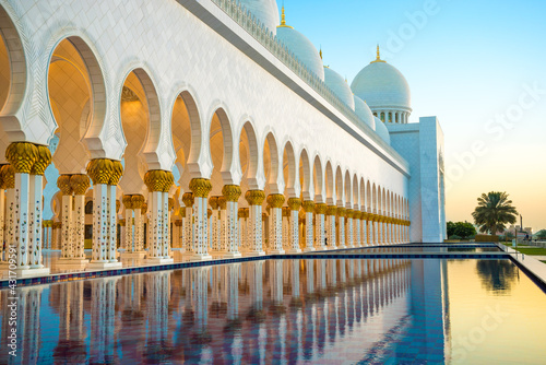 Sheikh Zayed Grand Mosque reflected in a pool at sunset.
