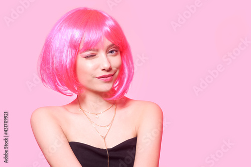 The girl in a pink wig, on a pink background, is happy, grimaces, smiles. Bright photo of a teenager, smart, party, dance. Anime pink cute girl