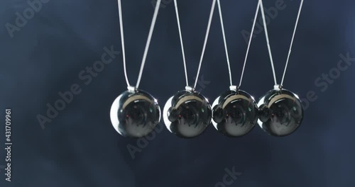 Close-up of Newton's Pendulum - metal balls hit one another and show energy conservation effect