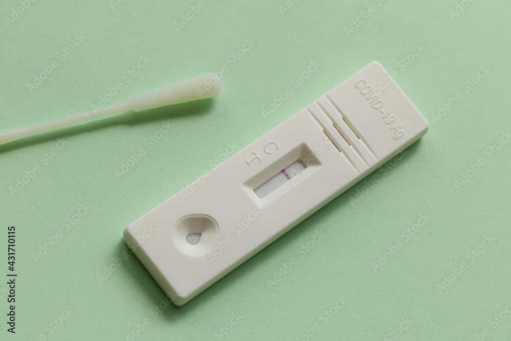 Close up of a negative antigen express coronatest self-test with cotton swap on a green surface Close up of a negative antigen express coronatest self-test with cotton swap on a green surface