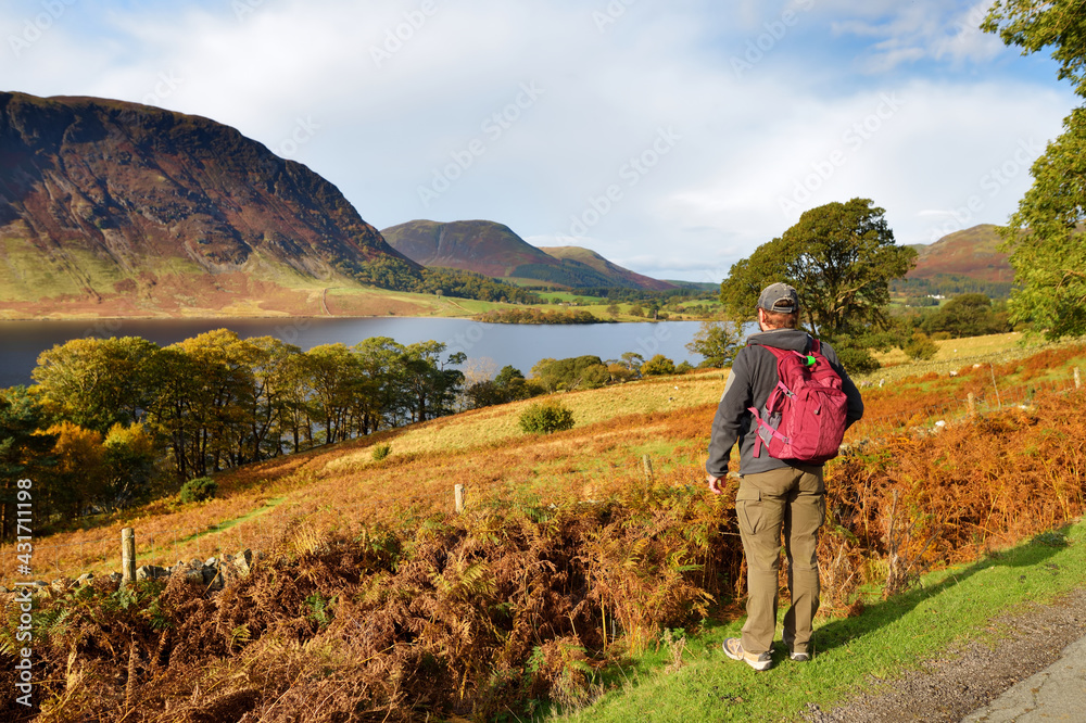 Male tourist enjoying the view of Crummock Water lake, located between Loweswater and Buttermere, in the Lake District in Cumbria, North West England. Male tourist enjoying the view of Crummock Water lake, located between Loweswater and Buttermere, in the Lake District in Cumbria, North West England.