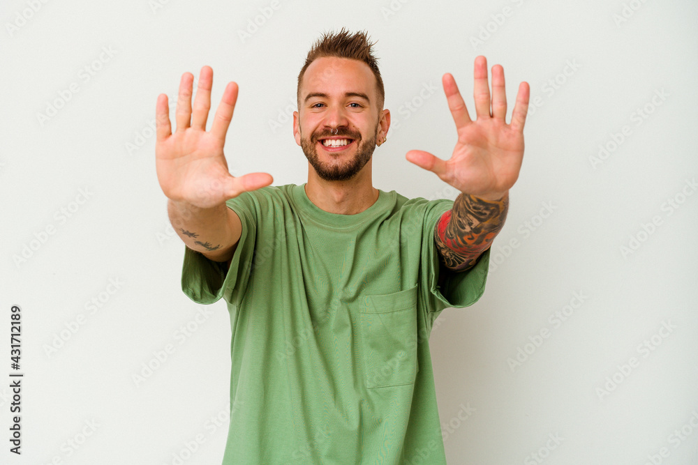 Young tattooed caucasian man isolated on white background showing number ten with hands. Young tattooed caucasian man isolated on white background showing number ten with hands.