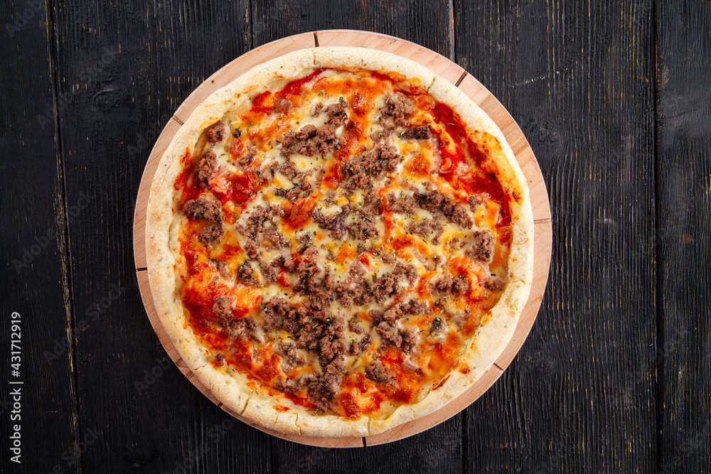 Pizza with minced meat and tomato sauce on the dark wooden background