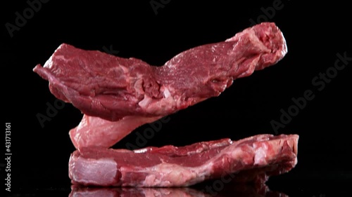 Flying pieces of raw beef steaks falling on table. Filmed on high speed cinema camera, 1000 fps. photo