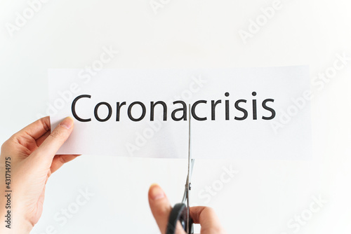Woman cuts the word corona crisis with scissors.