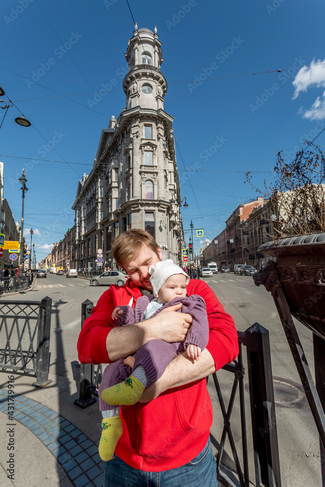 Outdoor portrait of young red-haired father holding his little toddler.