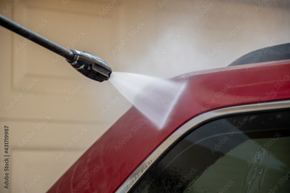 Washing a red car with high pressure washer cleaner.