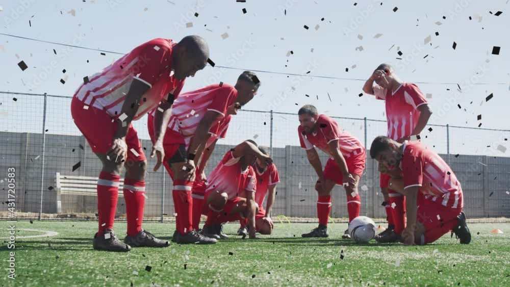 Confetti falling against against team of male soccer players sitting in disappointment