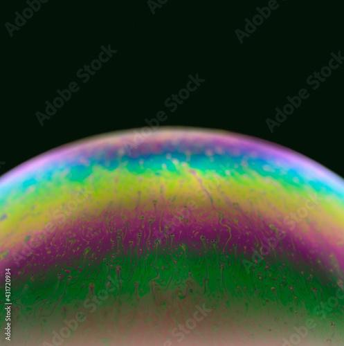 A Blurred soap bubble close-up on black background. Bright colors. A high resolution. Imitation of an unknown planet. Children's entertainment. Science fiction.