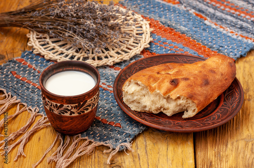 International Milk Day photo. Clay glass with milk and bread on a wooden table and homemade tablecloth