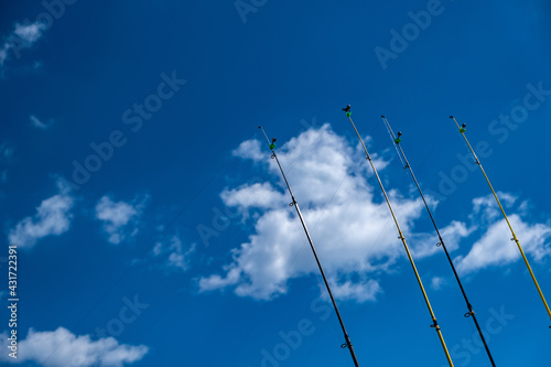 Four fishing rods in row. Blue sky background.