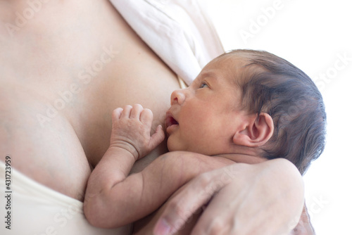 New born baby boy resting in mother's arms, close up of sleeping newborn baby aged 27 days on mother's chest