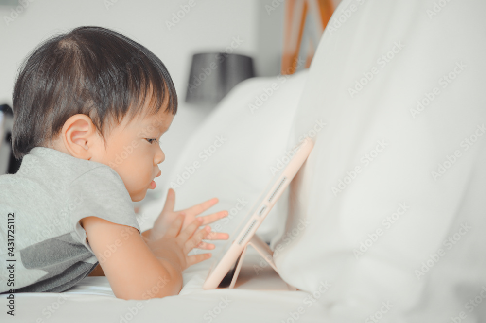 Little asian boy lying in bed and watch a story on touchscreen tablet,Early age education development. Video chat, video call. Little asian boy lying in bed and watch a story on touchscreen tablet,Early age education development. Video chat, video call.