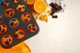 orange curd muffins with chocolate lie in a baking dish on a wooden tray on a white background with piaces of chocolate and oranges. Top view 
